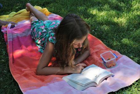 girl reading on a blanket outdoors under a tree